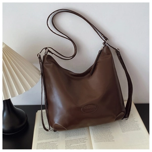 Detail of a brown leather Hobo bag with adjustable strap on a vintage book