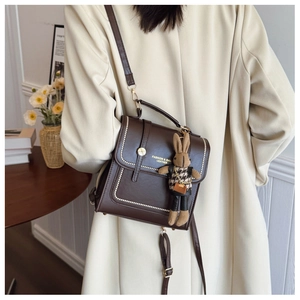 Detail of dark brown PU leather bag with white stitching and cute rabbit charm