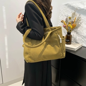Large mustard yellow corduroy tote bag with side pocket shown on shoulder