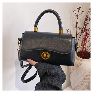 Détail d'un sac à main vintage en cuir noir avec fermoir doré et texture raffinée