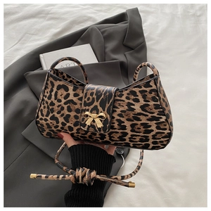 Close-up of leopard print handbag featuring a gold bow clasp and adjustable strap