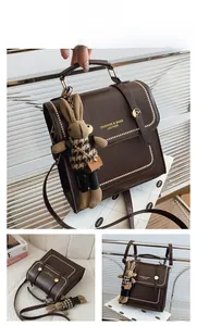 Detail view of coffee brown faux leather handbag with gold studs and cute rabbit pendant