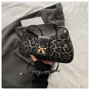 Detail of leopard print handbag with golden bow metal buckle on a dark grey suit