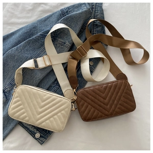 Detail of cream and brown crossbody bags with chevron quilting and wide textile straps