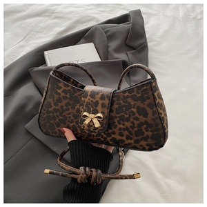 Detail of leopard print handbag featuring a gold bow buckle and textured PU leather