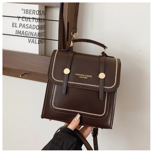Detail of dark brown leather tote bag with gold lettering and decorative rivets