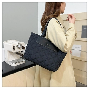 Detail of black quilted puffer tote bag with leather flap and fashion lettering