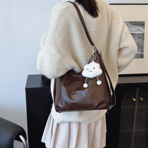 Women's brown faux leather hobo tote bag with cloud pendant shown from a side view