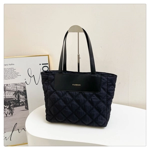 Close-up of black quilted nylon tote bag featuring a leather Fashion patch detail