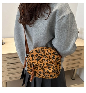Detail of leopard print corduroy crossbody bag with adjustable strap on a model