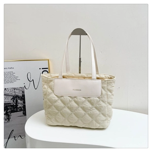 Close-up of beige quilted tote bag with diamond stitching and Fashion leather patch
