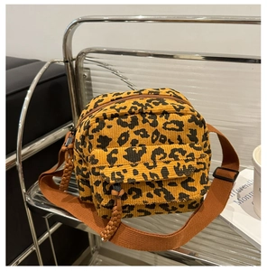 Close-up of leopard print corduroy crossbody bag with adjustable brown strap and front pocket