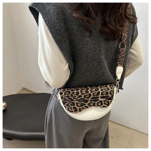 Detail of leopard print flap on white saddle bag with matching wide shoulder strap