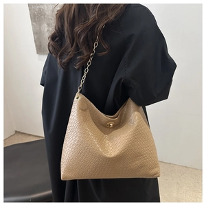 Detail of khaki woven hobo bag featuring a gold chain strap and metallic twist lock
