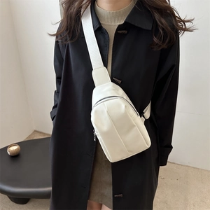 Minimalist white crossbody chest bag with adjustable strap worn on a black coat