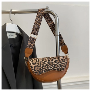 Detail of the leopard print flap and wide strap on the brown saddle bag displayed