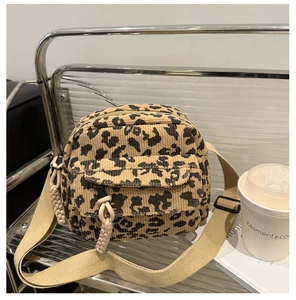 Close-up of leopard print corduroy crossbody bag with woven zip pullers and nylon strap