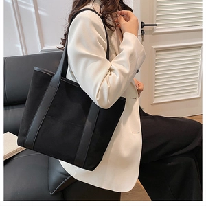 Detail of a large black suede tote bag shown in a minimalist professional office setting