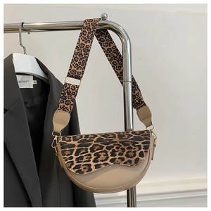 Detail of leopard print saddle bag with wide strap and golden hardware on display