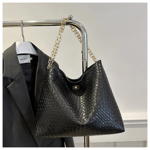 Close-up of black woven shoulder bag with elegant gold chain straps and twist lock closure