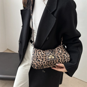 Chic leopard print shoulder bag with gold bow clasp worn by model in black coat