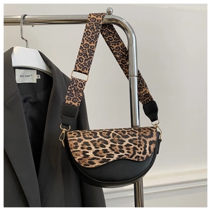 Detail of a leopard print saddle bag with gold metal hardware and wide adjustable strap