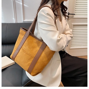 Detail of yellow suede tote bag featuring contrast brown straps and stitched front pocket