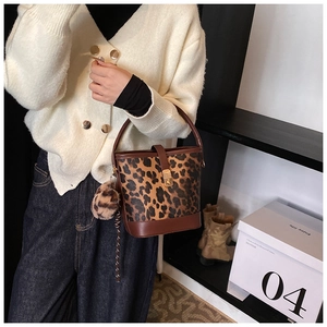 Detail of vintage leopard print bucket bag with brown leather strap and plush charm