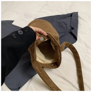 Detail of the brown faux shearling bucket bag featuring a secure metal magnetic closure