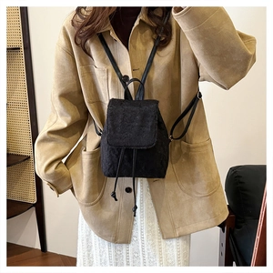 Mini sac à dos en peluche noire avec cordon de serrage et rabat porté par un modèle