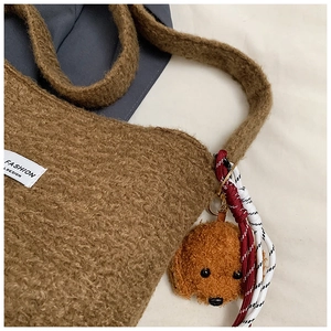 Close-up of brown faux shearling bucket bag with teddy dog charm and fashion tag