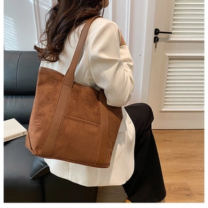 Detail of the brown suede tote bag showing texture and handle contrast on a model