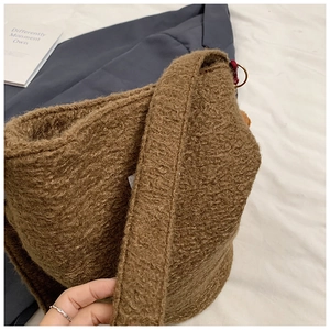 Close-up of brown wool plush texture and wide shoulder strap of a winter bucket bag