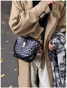 Detail of black and white leopard bucket bag with gold metal buckle and fur pompom