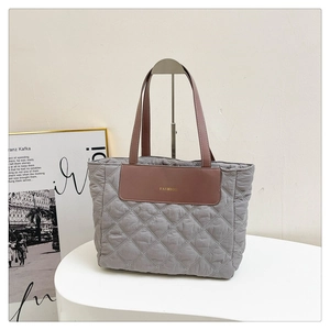 Detail of grey quilted nylon tote bag with brown leather handles and FASHION patch