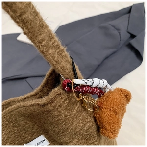 Detail of brown fleece tote bag featuring a plush bear charm and woven rope accessories