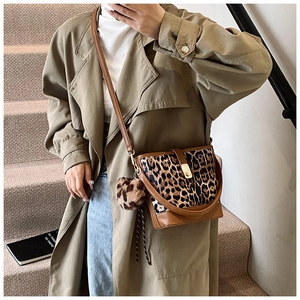 Close-up of leopard print bucket bag with plush charm and golden knob buckle detail