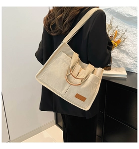 Detailed macro view of cream corduroy tote bag showing fashion label and leather handle