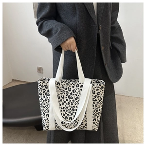 Détail d'un grand sac cabas à motif léopard avec des poignées en toile tissée blanche solide