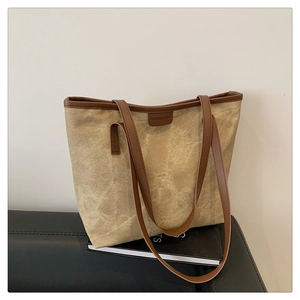 Detail of minimalist coffee canvas tote bag with brown leather trim and fashion logo