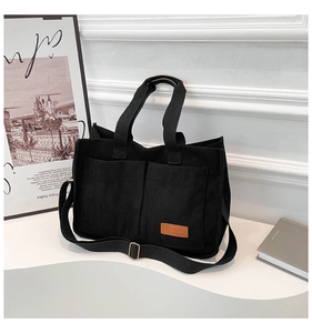 Close-up of black corduroy tote bag featuring two front pockets and a fashion leather patch