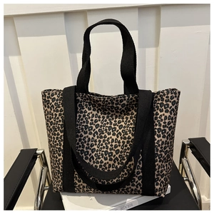Détail du sac cabas imprimé léopard avec doubles anses posé sur des livres blancs et une chaise
