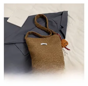 Detailed view of brown teddy wool bucket bag with 'LOVE FASHION' label and bear charm