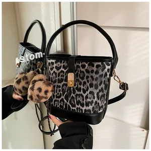 Detail view of leopard print bucket bag featuring plush pom-poms and gold metal lock