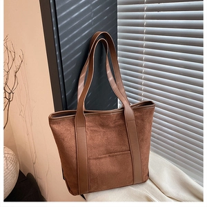 Detail of a dark brown suede tote bag featuring contrast stitching and leather handles