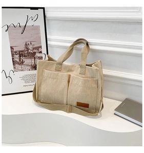 Detail of corduroy tote bag featuring dual front pockets and adjustable woven shoulder strap