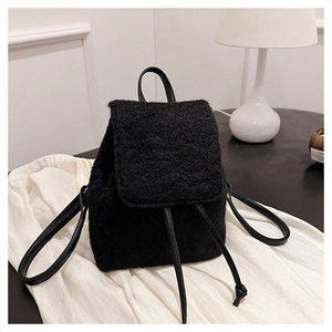 Détail d'un sac à dos en fausse fourrure noire avec cordon sur une table moderne