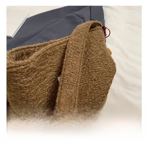 Detail of plush tote handle with woven accents and metallic rings on teddy fur bag