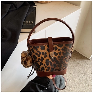 Close-up of leopard print bucket bag featuring gold twist-lock and fuzzy pom-pom charm