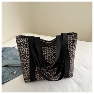 Détail du sac cabas en toile à motif léopard avec deux anses en sangle noire pour l'épaule